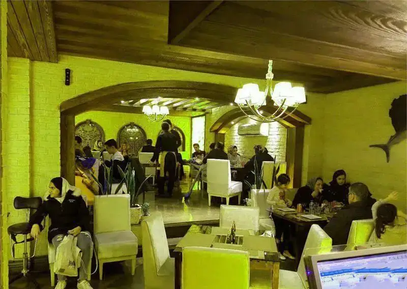 نمایی از محیط داخلی فست فود جاسنتو با مشتریان متعدد، میز و صندلی‌های راحت و طراحی سنتی-مدرن با سقف‌های چوبی و طاق‌های آجری.