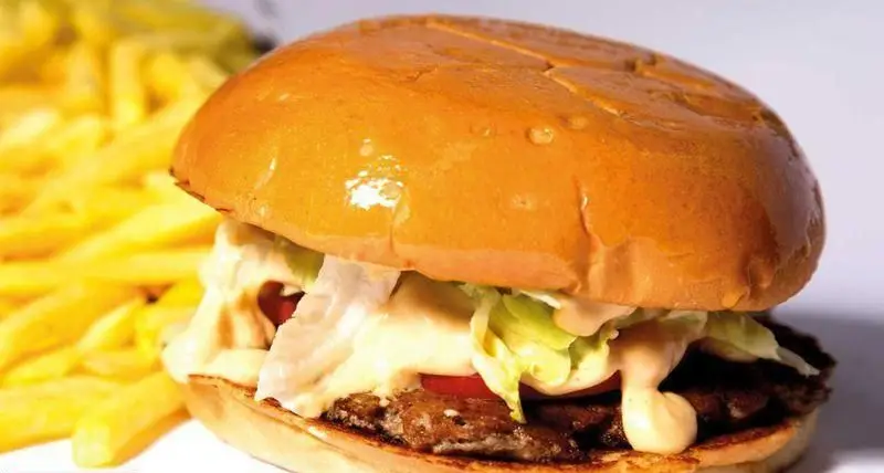 یک برگر خوشمزه از تهران برگر با نان طلایی، پتی گوشت آبدار، کاهو، گوجه و سس مخصوص، به همراه سیب زمینی سرخ کرده.