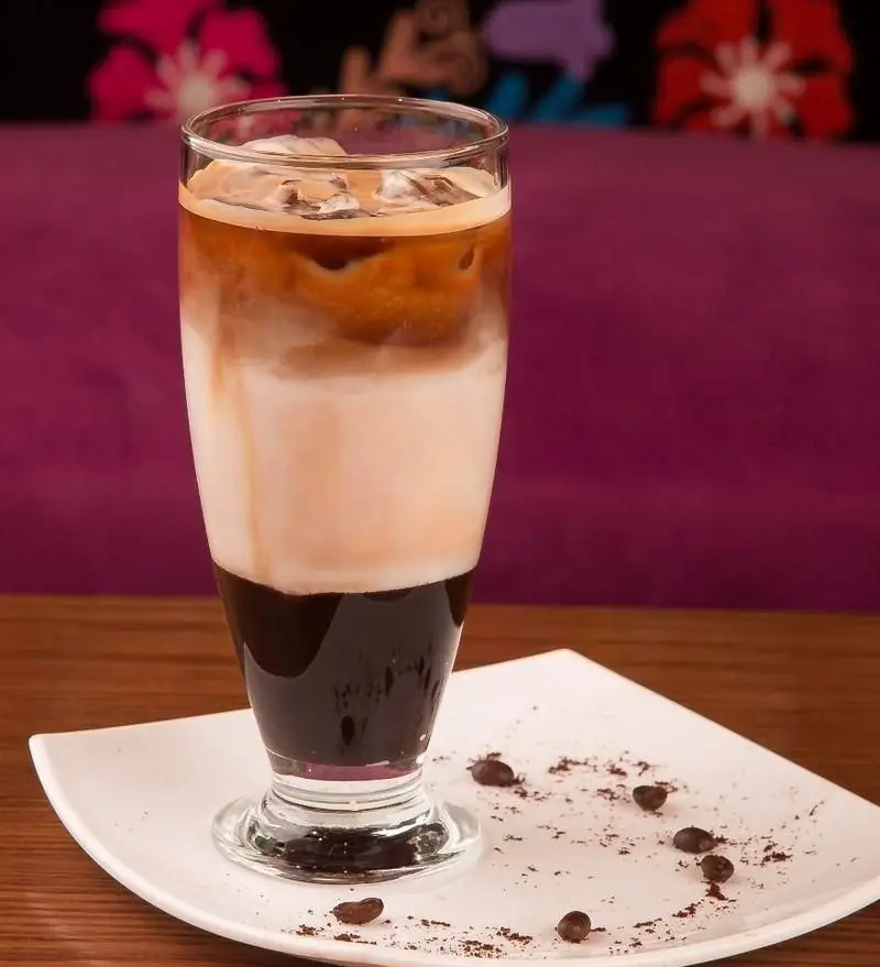 آیس لاته لایه لایه و خوش‌رنگ کافه رستوران آشا، یک نوشیدنی عالی و خنک با دانه‌های قهوه، برای تجربه‌ای دلپذیر.
