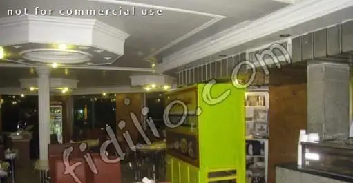 نمایی از فضای داخلی رستوران فرنگی قاراشی همایون با سقف تزئینی، نورپردازی زرد، مبلمان راحتی و کابینت سبز رنگ، فضایی دنج و شیک.