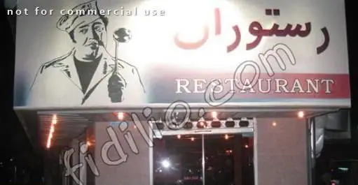 تابلوی درخشان رستوران فرنگی قاراشی همایون با تصویر سرآشپز کلاهدار و ملاقه در دست، همراه با نام "رستوران" و "RESTAURANT" بر فراز ورودی.