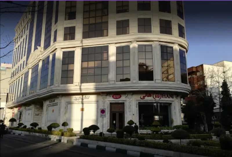 نمای بیرونی و ساختمان بزرگ رستوران هانی با طراحی شیک و مدرن، در یک روز آفتابی، واقع در نبش یک خیابان پرتردد.