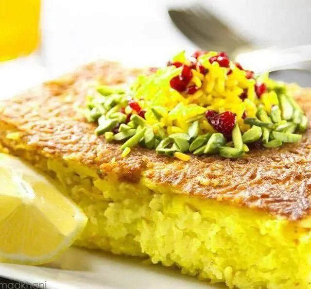 ته چین مرغ زعفرانی مجلسی، غذای خانگی مادرانه مادر سالار با ته دیگ طلایی، تزئین شده با زرشک، خلال پسته و لیمو.