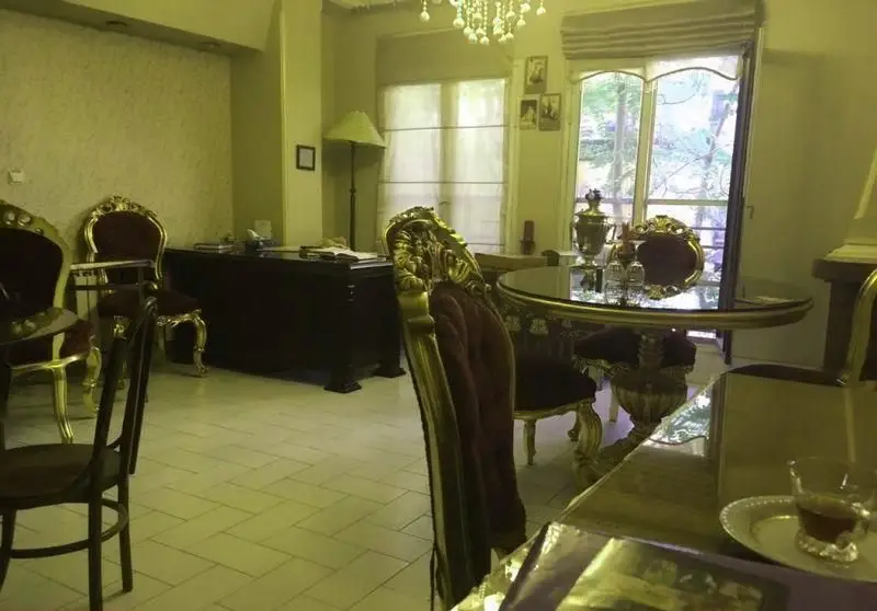 تصویری از فضای دلنشین و مجلل "غذای خانگی مادرانه مادر سالار" با دکوراسیون کلاسیک، میز و صندلی‌های شیک و سماور.