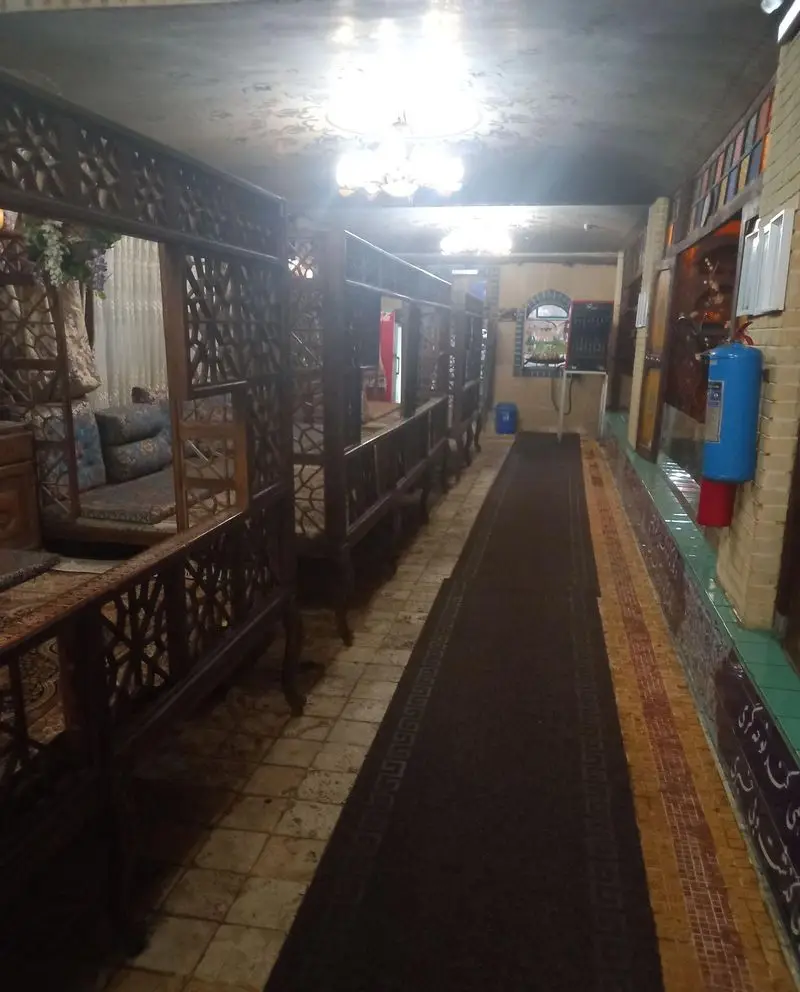 فضای داخلی زیبای رستوران سنتی هودین با تخت‌های چوبی منبت‌کاری شده، راهروی دلنشین و دکوراسیون خاص برای تجربه غذایی لذت‌بخش.