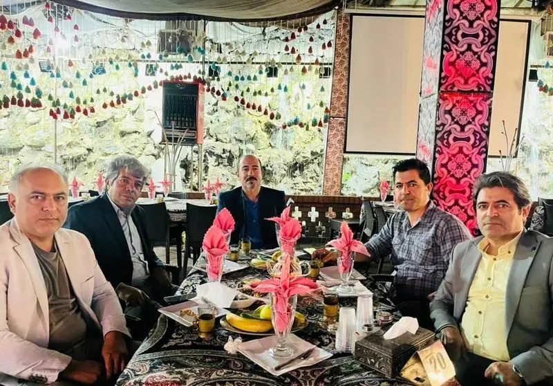 شش مرد در رستوران هودین، دور میزی مملو از غذا و نوشیدنی، در فضایی دلنشین و با پذیرایی عالی مشغول دورهمی هستند.