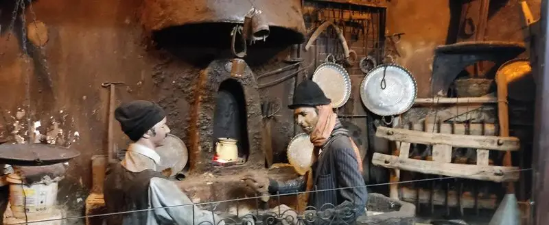 ماکتی دیدنی از یک کارگاه سنتی ایرانی با اجاق قدیمی و ظروف مسی در رستوران هودین، یادآور تاریخ و فرهنگ غنی غذایی.