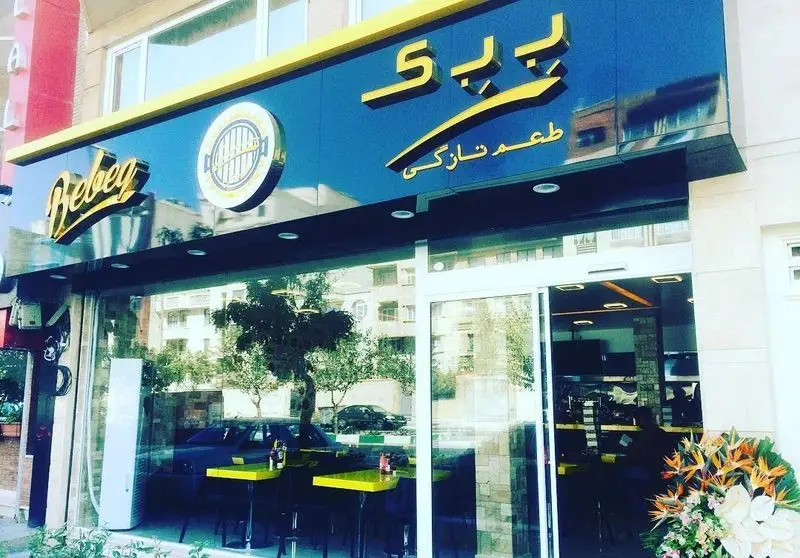 نمای بیرونی جذاب فست فود ببک با تابلوی شیک طلایی و مشکی، لوگوی گریل و شعار طعم تازگی. یک رستوران مدرن برای ساندویچ و برگرهای خوشمزه.