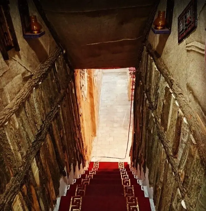 تصویری از پله‌های ورودی کافه سنتی ترنه با فرش قرمز و حاشیه‌های طلایی، دکوراسیون چوبی و معماری سنتی که به راهرویی آرام منتهی می‌شود.