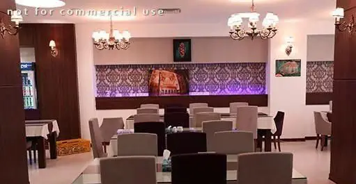 فضای داخلی رستوران غذای فرزانه با میز و صندلی‌های مرتب، لوسترهای زیبا و دیوارپوش‌های طرح‌دار با نورپردازی بنفش، محیطی شیک و دلنشین برای پذیرایی.