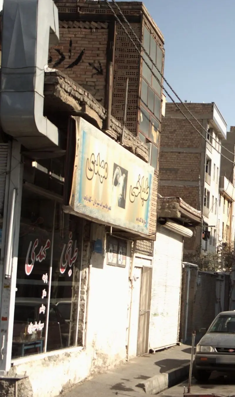 تصویر نمای بیرونی طباخی مهدی با تابلوی مشخص، رستوران سنتی کله پاچه و غذاهای ایرانی در کنار خیابان در روز آفتابی.