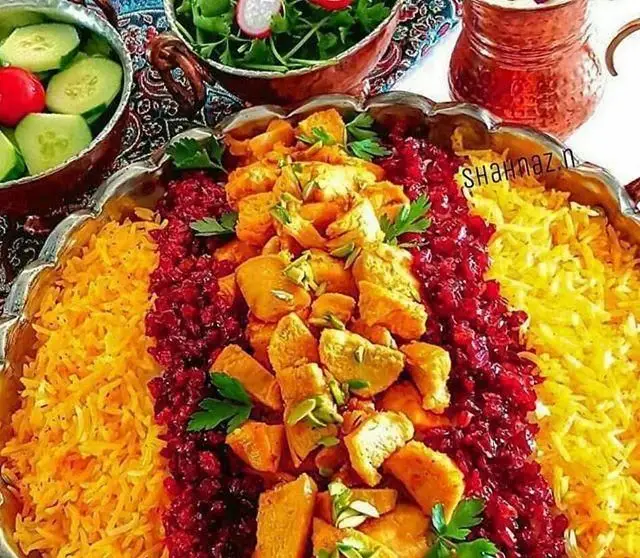 زرشک پلو با مرغ زعفرانی، برنج دو رنگ و سالاد تازه در رستوران ایرانی کاه گل. تزئین شده با پسته و سبزی، غذای اصیل ایرانی.