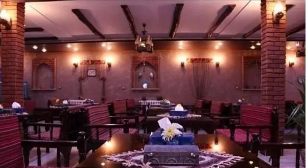 فضای داخلی رستوران ایرانی کاه گل با دکوراسیون سنتی، میز و صندلی‌های چوبی و نورپردازی گرم، محیطی دلنشین برای صرف غذا.