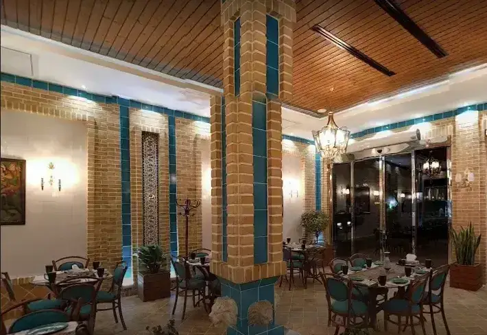 تصویر فضای داخلی رستوران سنتی ریحون با آجرکاری، کاشی آبی، سقف چوبی، میزهای شیک و نورپردازی زیبا مناسب خانواده.