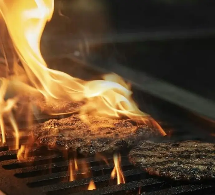 برگرهای بمب آرش روی گریل با شعله‌های آتش، در حال آماده‌سازی برای یک تجربه بی‌نظیر فست‌فود. طعمی واقعی از همبرگر.