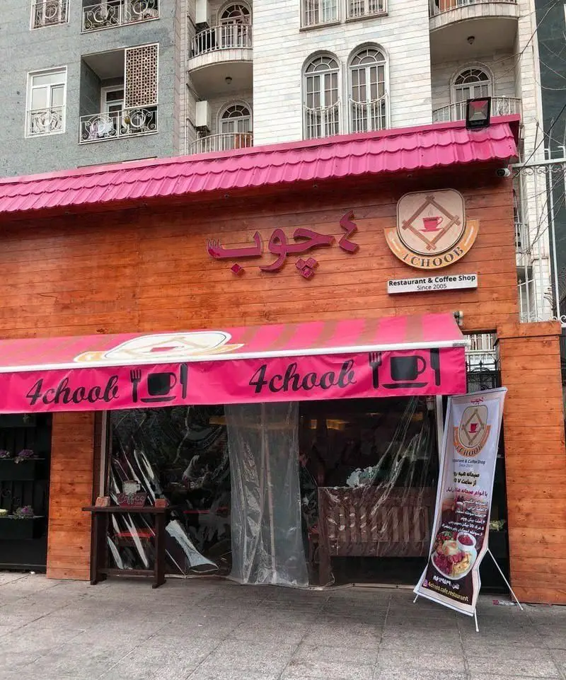 نمای بیرونی کافی شاپ و رستوران 4 چوب با دکوراسیون چوبی، سقف صورتی و تابلوی اسم، آماده پذیرایی از مهمانان.