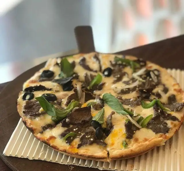 پیتزای خوشمزه گوشت و سس مخصوص فست فود چهل سی، با تکه‌های گوشت، زیتون سیاه، فلفل دلمه سبز، ریحان و کنجد.