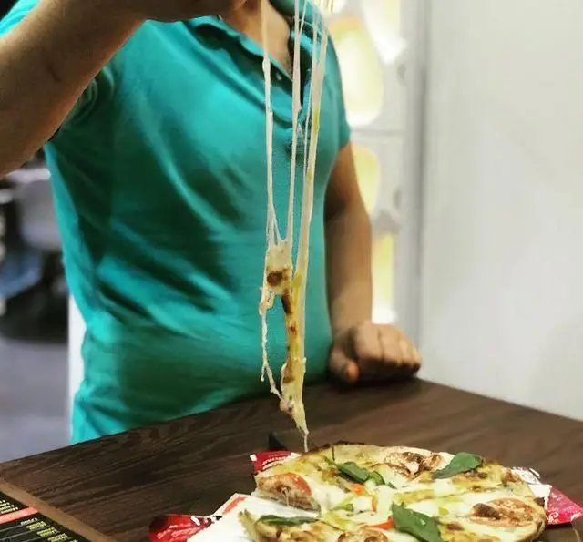 تصویری جذاب از پیتزای داغ و تازه با پنیر کشسان و چاشنی‌های خوش‌رنگ در فست فود چهل سی. یک تجربه لذیذ!