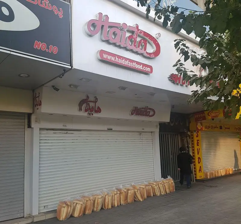 ورودی فروشگاه ساندویچ هایدا با کرکره های بسته و ده ها بسته نان تازه ساندویچی برای آماده سازی روز کاری جدید.