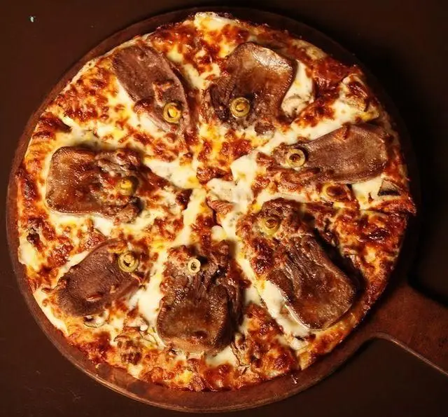 پیتزا زبان و زیتون کافه رستوران گردو، با پنیر موزارلای آب شده، گوشت زبان طعم‌دار و حلقه‌های زیتون سبز. یک غذای خاص و خوشمزه ایتالیایی.