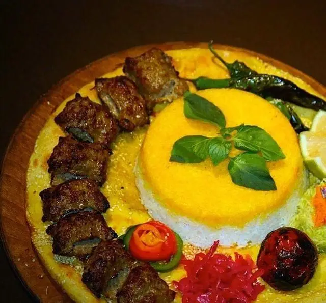 سینی کباب و برنج زعفرانی خوش عطر کافه رستوران گردو. غذای اصیل ایرانی با مخلفات تازه شامل فلفل، لیمو و سبزی معطر.