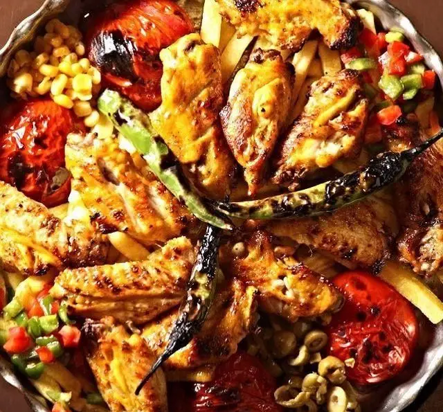 بشقاب لذیذ بال و کتف کبابی، سیب زمینی سرخ کرده، گوجه و فلفل کبابی، ذرت و زیتون. غذای خوشمزه کافه رستوران گردو.