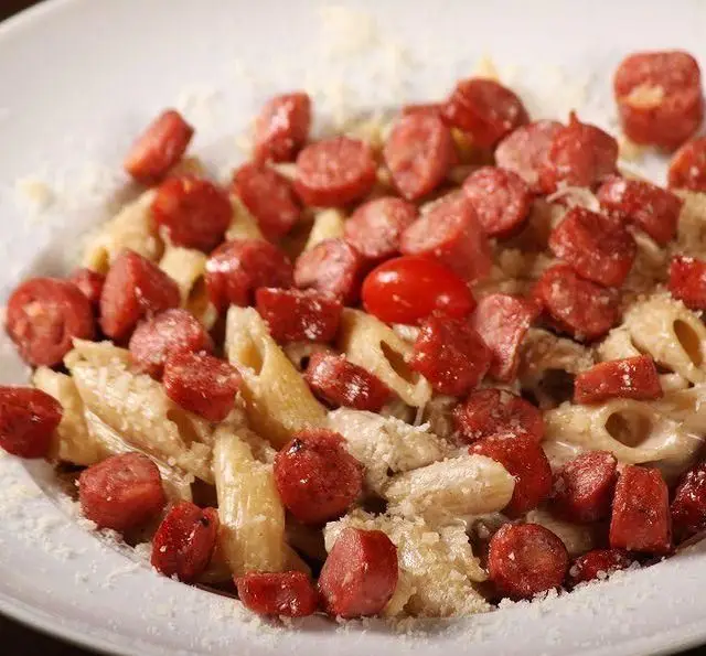 غذای خوش طعم پنه پاستا با سس خامه‌ای غنی، قطعات سوسیس برشته، گوجه فرنگی گیلاسی و پنیر فراوان از کافه رستوران گردو.