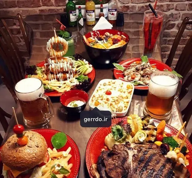 میز پر از غذاهای لذیذ و متنوع کافه رستوران گردو شامل استیک، برگر، پاستا، سالاد و نوشیدنی‌های خنک برای مشتریان.
