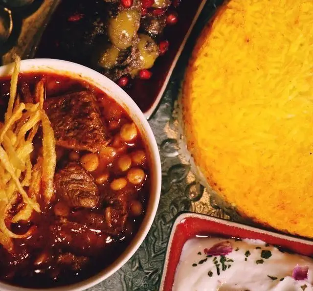 نمایی جذاب از سفره ایرانی کافه رستوران گردو: خورشت لذیذ با گوشت و لپه، ته دیگ زعفرانی طلایی و ترشی انار و زیتون.