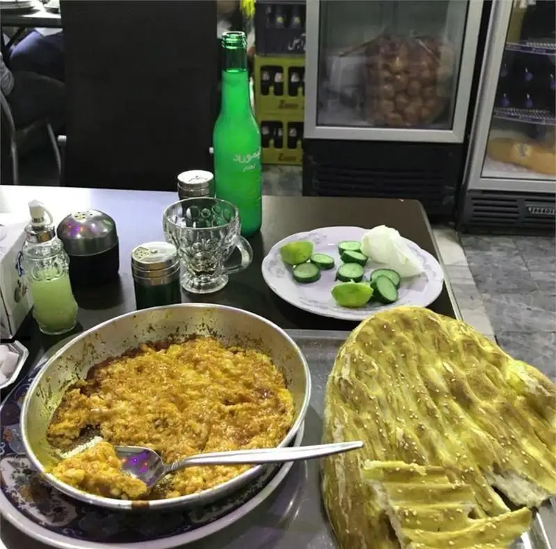 دیزی سرای اختیار: میز غذای لذیذ شامل دیزی سنتی ایرانی، نان تازه داغ، خیار و لیمو برای یک تجربه دلپذیر در رستوران.