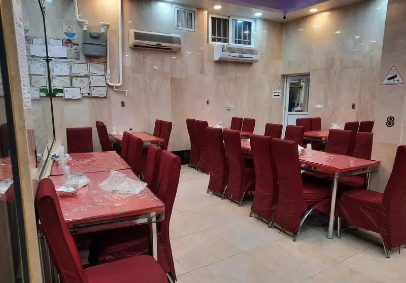 فضای داخلی تمیز و مرتب رستوران زیتون، با ردیف میز و صندلی‌های قرمز رنگ، آماده استقبال از مهمانان. محیطی آرام و دنج برای تجربه یک وعده غذای دلپذیر.