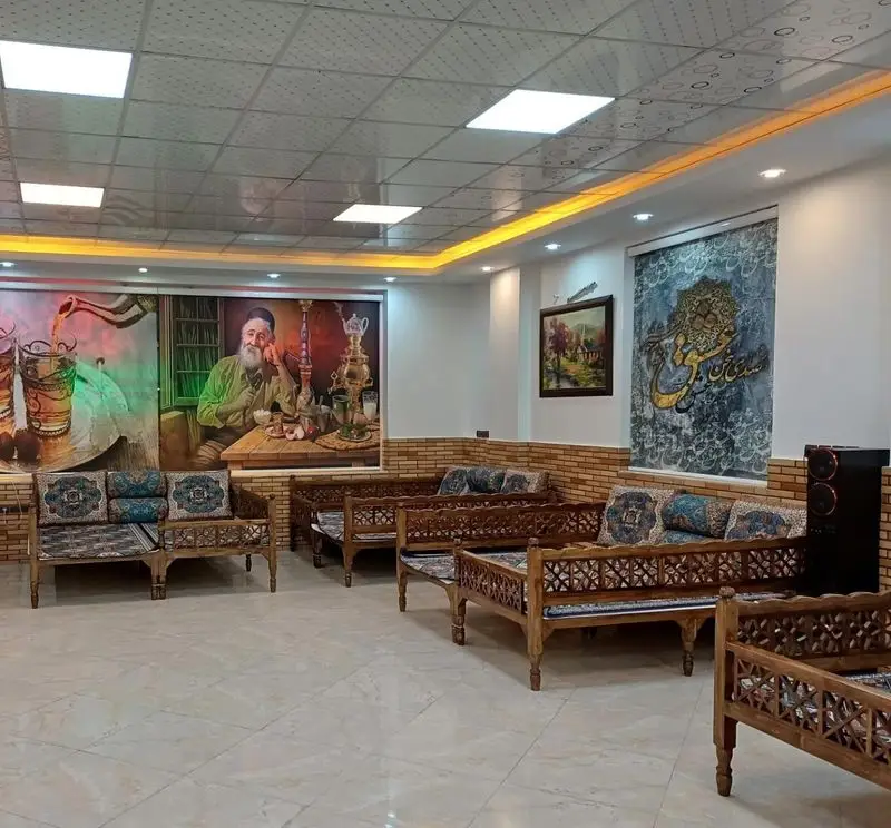 فضای دلنشین رستوران سنتی منوچ با مبلمان چوبی منبت‌کاری شده، نقاشی‌های دیواری و فضای دنج سنتی ایرانی.