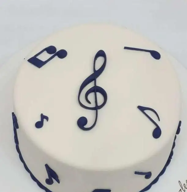 کیک تولد سفید و شیک با تزیینات نت‌های موسیقی و کلید سل آبی تیره، یک کیک سفارشی جذاب از قنادی سهند برای علاقه‌مندان به موسیقی