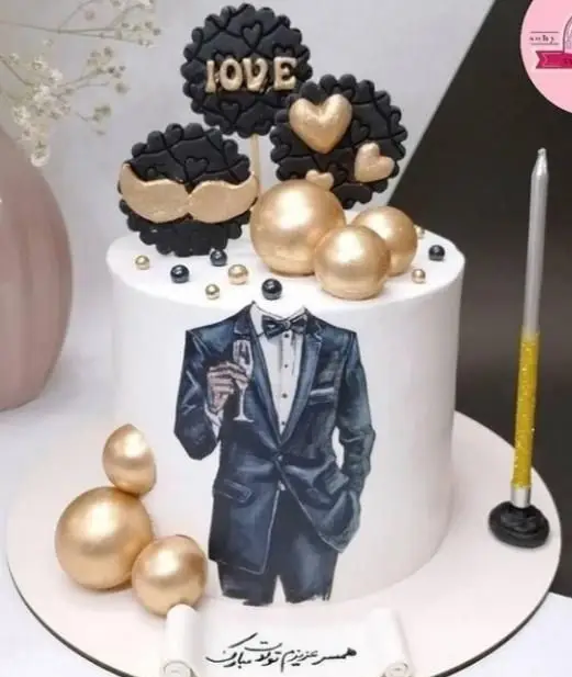 کیک تولد مردانه شیک قنادی سهند با تم مشکی طلایی، تزئین کت و شلوار، کلاهک‌های LOVE، قلب و سبیل طلایی و گوی‌های براق.