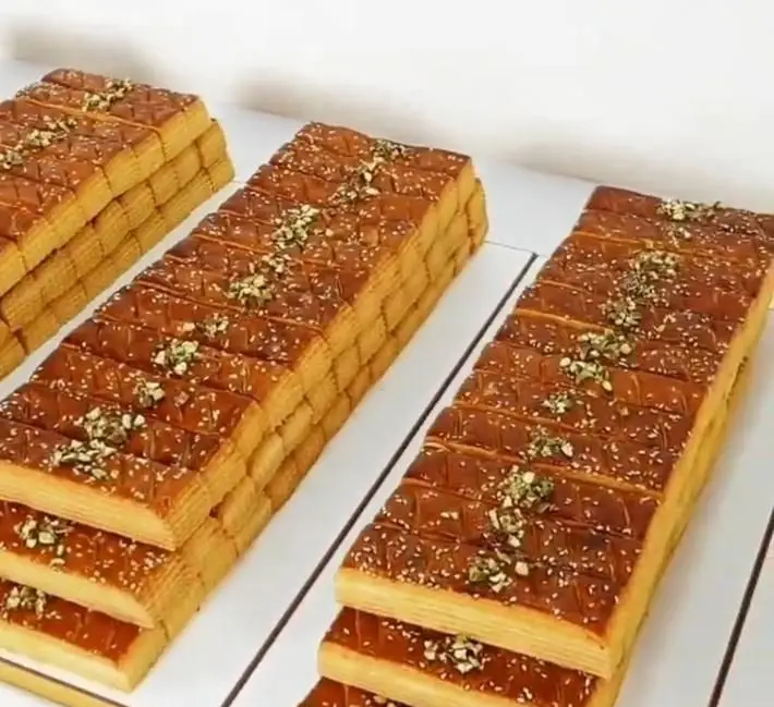 دسرهای لایه‌ای و مجلسی قنادی سهند با روکش کاراملی، کنجد و پسته خرد شده، آماده برای پذیرایی‌های شیک و خاص شما.