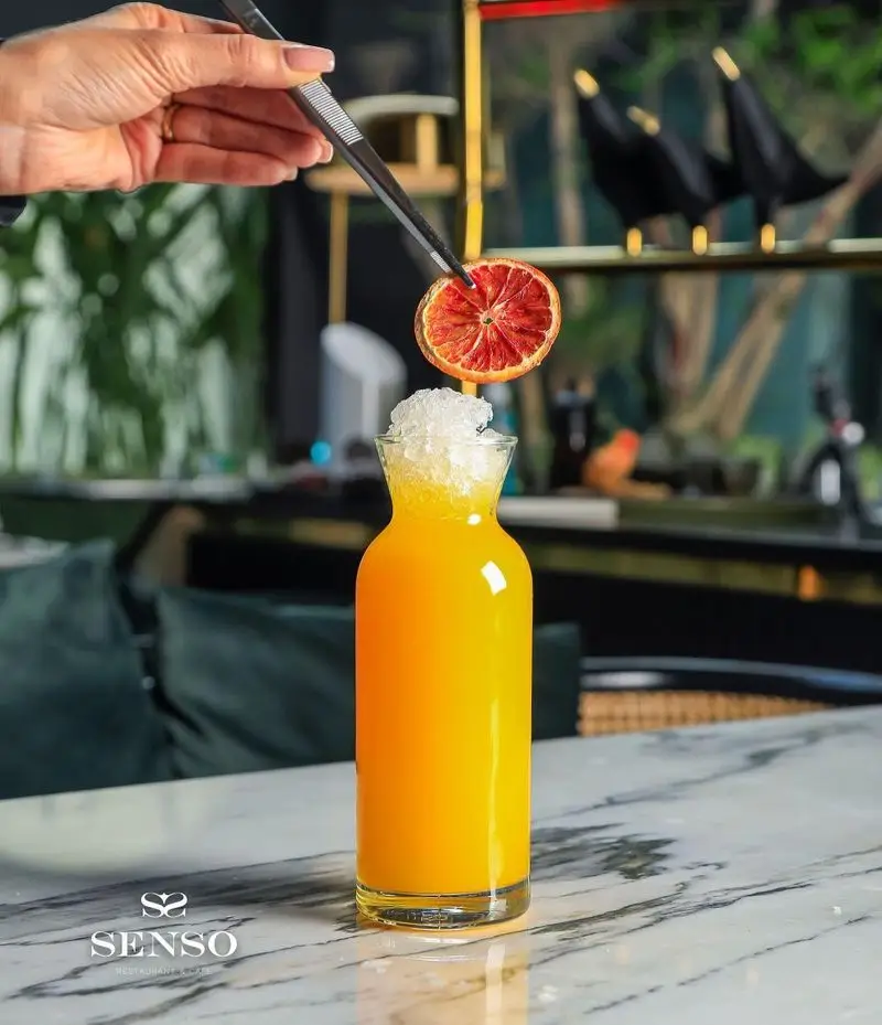 نوشیدنی خنک آب پرتقال تازه و گوارا با تزیین میوه خشک در کافه رستوران ایتالیایی سنسو، تجربه‌ای دلنشین و تابستانی.
