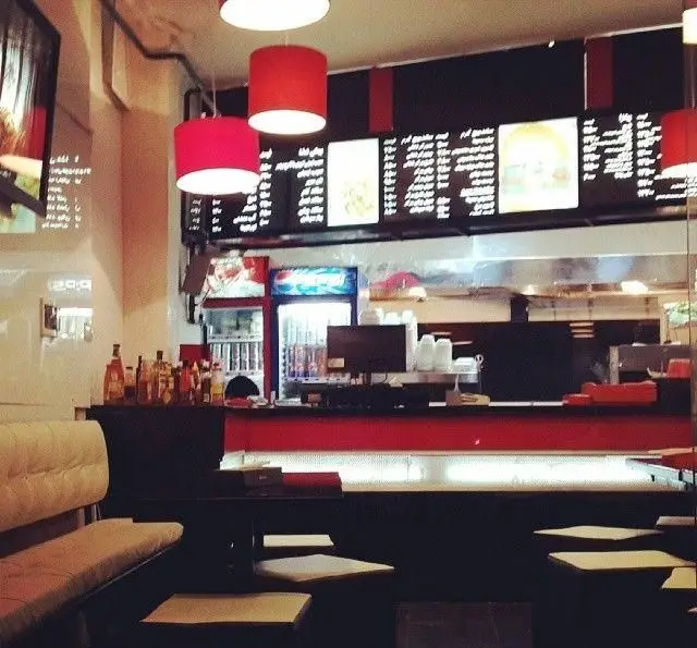 فضای داخلی مدرن فست فود رسپینا با دکوراسیون قرمز و مشکی، منوهای دیجیتال جذاب و آماده سازی غذا در محیطی دلپذیر برای مشتریان.