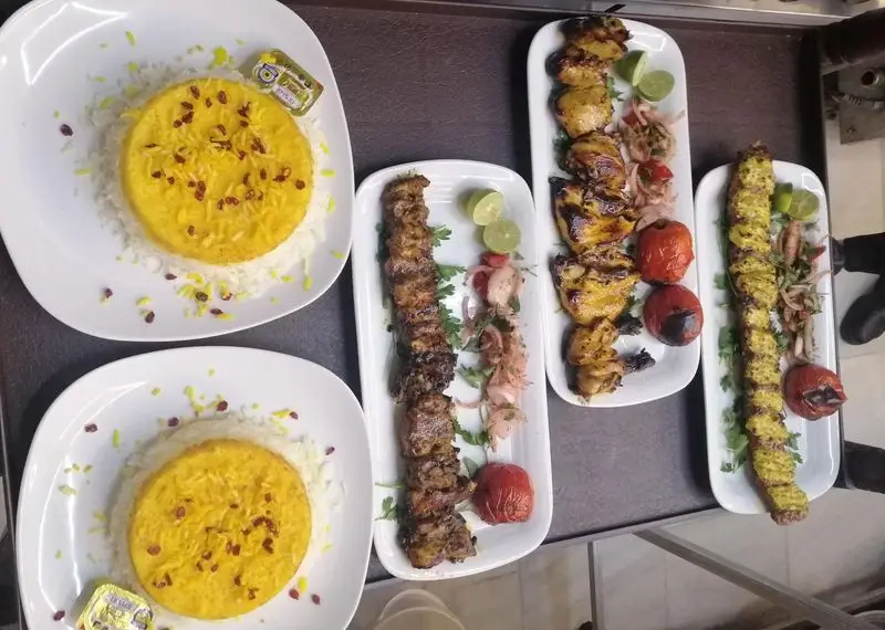 انواع کباب لذیذ ایرانی شامل جوجه کباب و کوبیده به همراه چلو زعفرانی در باغ رستوران ریحانه. تجربه غذای اصیل و خوشمزه.