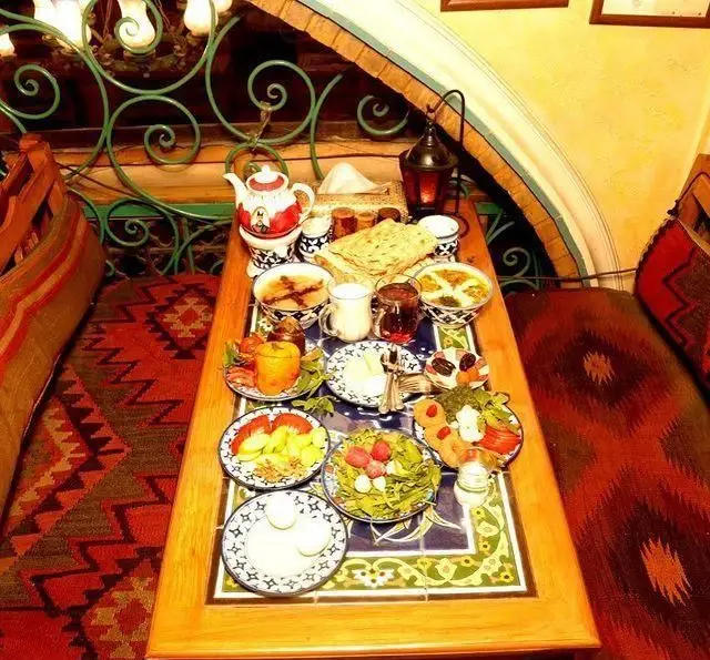 سفره خانه سنتی باغ صبا: میزی دلنشین از صبحانه یا وعده غذایی ایرانی با نان، چای، تخم مرغ و سالاد در محیطی گرم و سنتی.