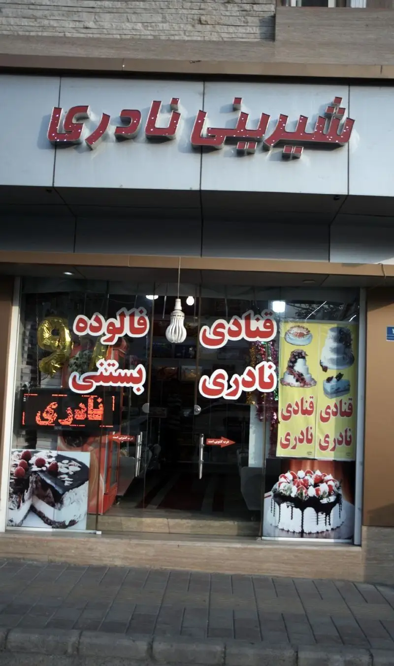عکس درب ورودی فروشگاه شیرینی نادری ارائه دهنده کیک‌های تولد، شیرینی‌های تازه و متنوع، به همراه فالوده و بستنی سنتی.