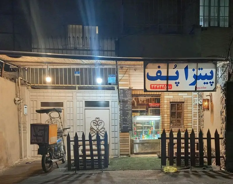 فست فود پیتزا پف در شب با تابلو روشن و شماره ۳۳۷۷۳۲۵۰. آماده پذیرایی و ارسال پیتزا، ساندویچ و غذاهای خوشمزه با پیک موتوری.