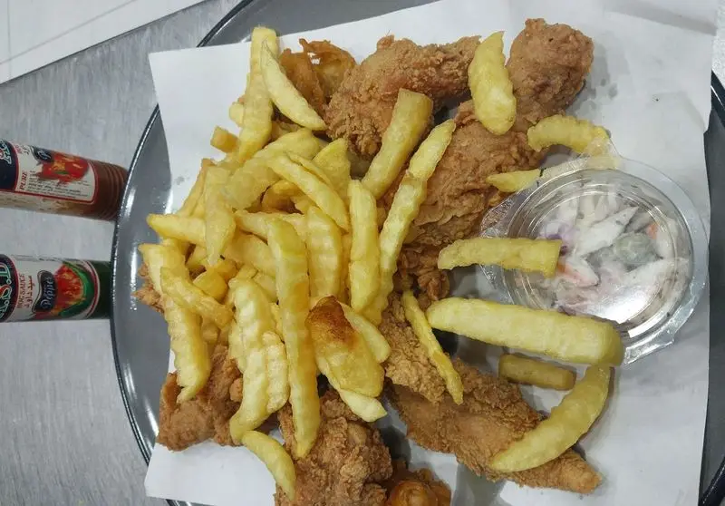 غذای فست فود آفتابگردان: مرغ سوخاری کریسپی، سیب زمینی سرخ کرده ترد و سالاد کلم، یک وعده لذیذ و پرطرفدار.