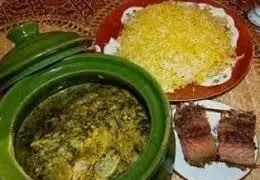 یک سفره غذای محلی لذیذ گیلانی از گیلان خوراک تالش شامل خورشت سنتی در ظرف سبز، پلو زعفرانی و ماهی کباب خوشمزه.