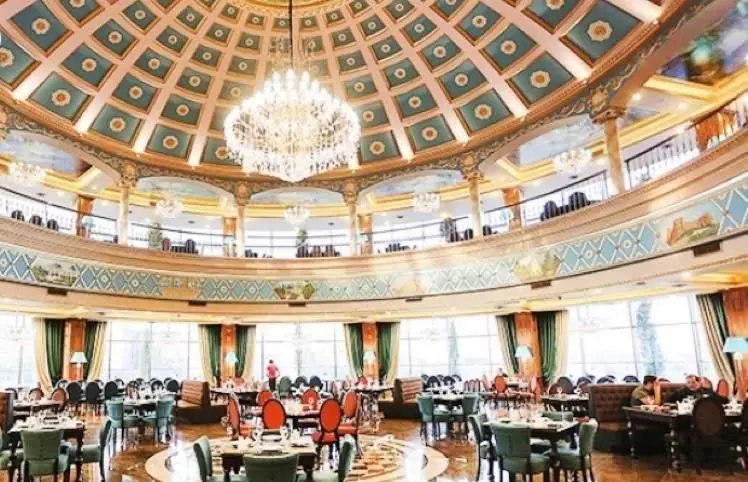 فضای داخلی مجلل کافی شاپ کاخ لیدوما با سقف گنبدی زیبا، لوستر باشکوه و چیدمان لوکس میز و صندلی برای تجربه ای خاص.