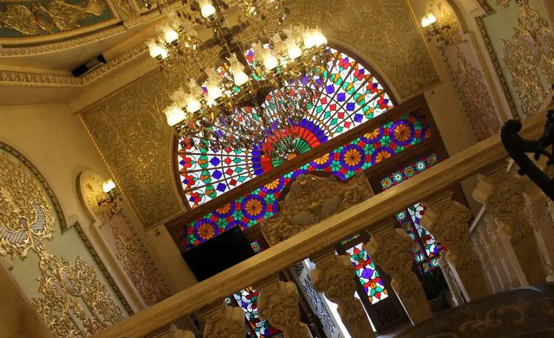 دکوراسیون داخلی خیره‌کننده کاخ رستوران نقش جهان با پنجره‌های ارسی سنتی، سقف و دیوار طلاکاری، و چلچراغ مجلل.