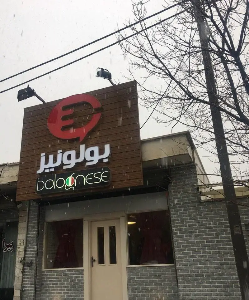 تابلوی روشن رستوران بولونیز، متخصص غذای ایتالیایی و پاستا. نمای بیرونی مدرن در هوای برفی، با لوگوی قرمز بولونیز و پرچم ایتالیا.