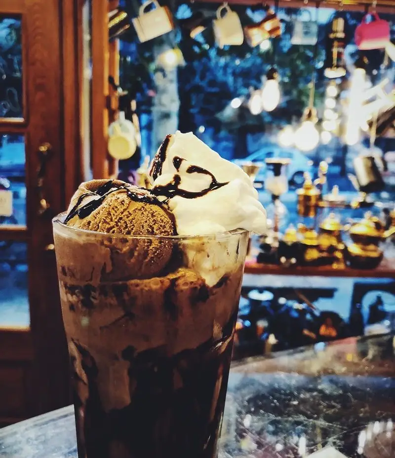 بستنی و میلک شیک شکلاتی با خامه و سس شکلات در کافه ایستگاه (لاله)، لذت شیرین در فضایی دنج و خاطره‌انگیز.