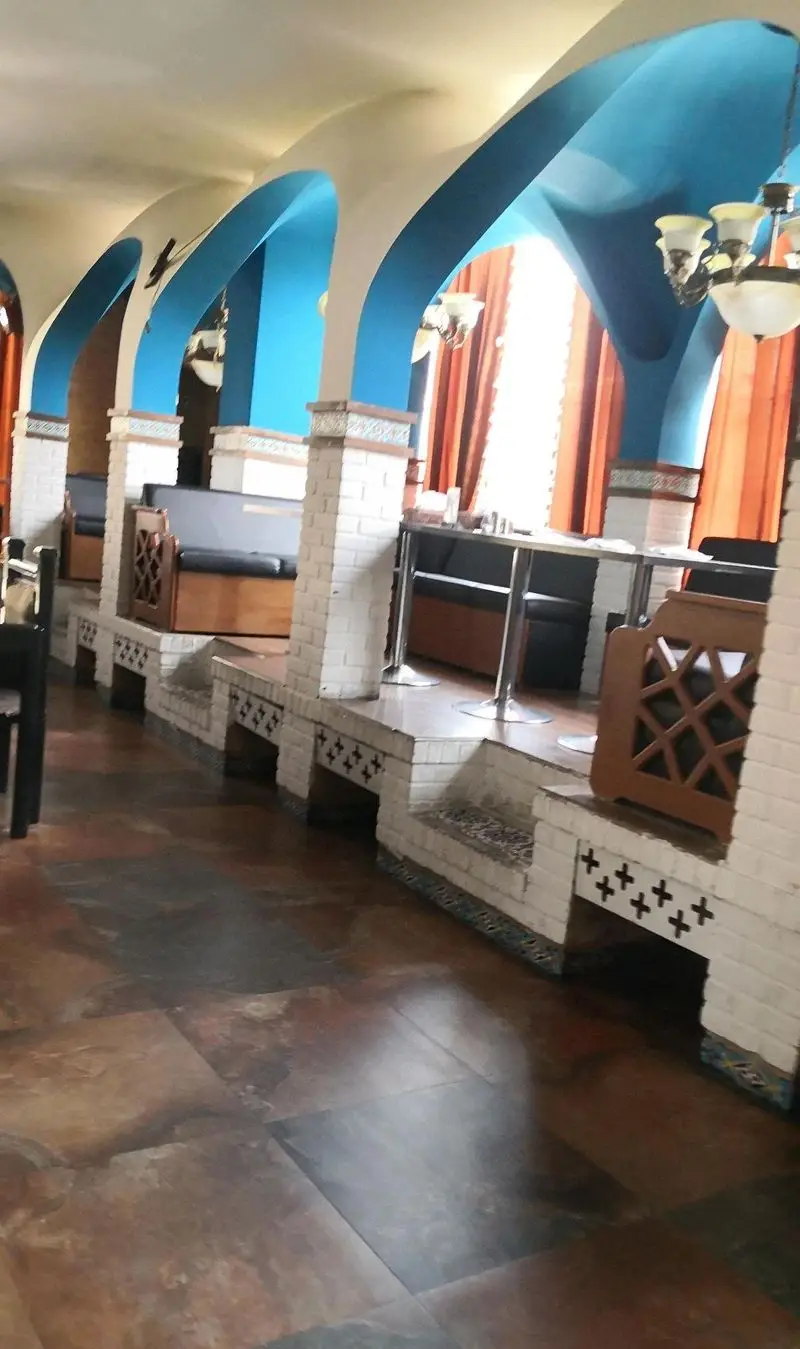 فضای داخلی زیبا و مدرن رستوران شهربانو با آرک‌های آبی رنگ، دیوارهای آجری سفید، میز و صندلی راحت و محیطی دلنشین.