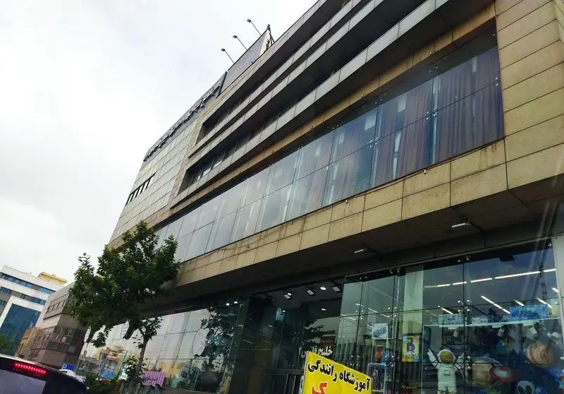 نمای بیرونی ساختمان مدرن رستوران شهربانو در یک روز ابری، با نمای شیشه‌ای و سنگی، همراه با درختان سبز در کنار خیابان.