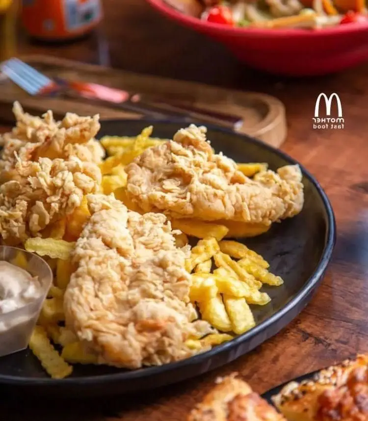 فست فود مادر: بشقاب وسوسه‌انگیز مرغ سوخاری ترد و سیب‌زمینی سرخ‌کرده طلایی با سس، همراه با سالاد تازه و اشتهاآور.